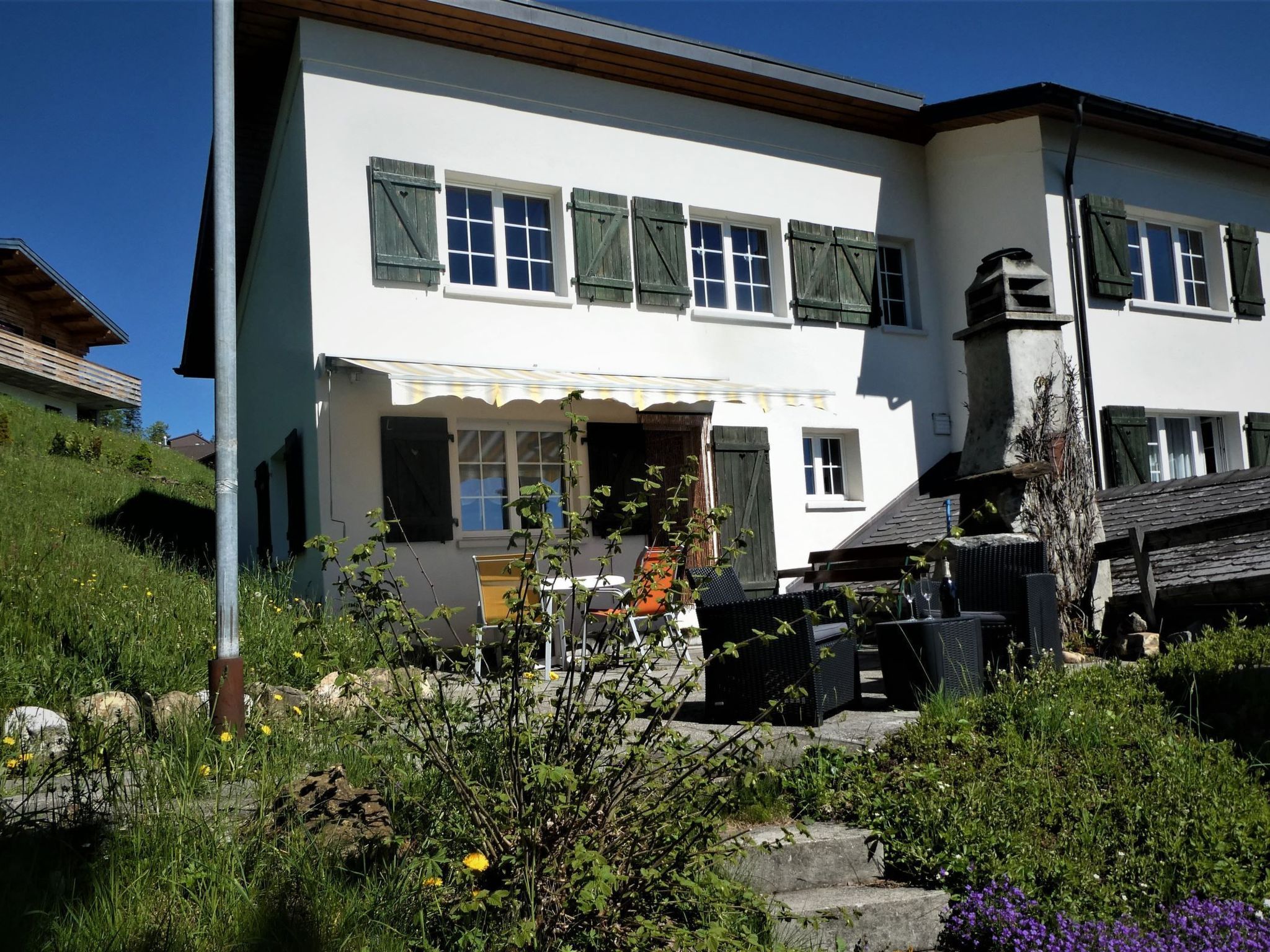A two-story building with a balcony, a covered entrance, and outdoor seating.