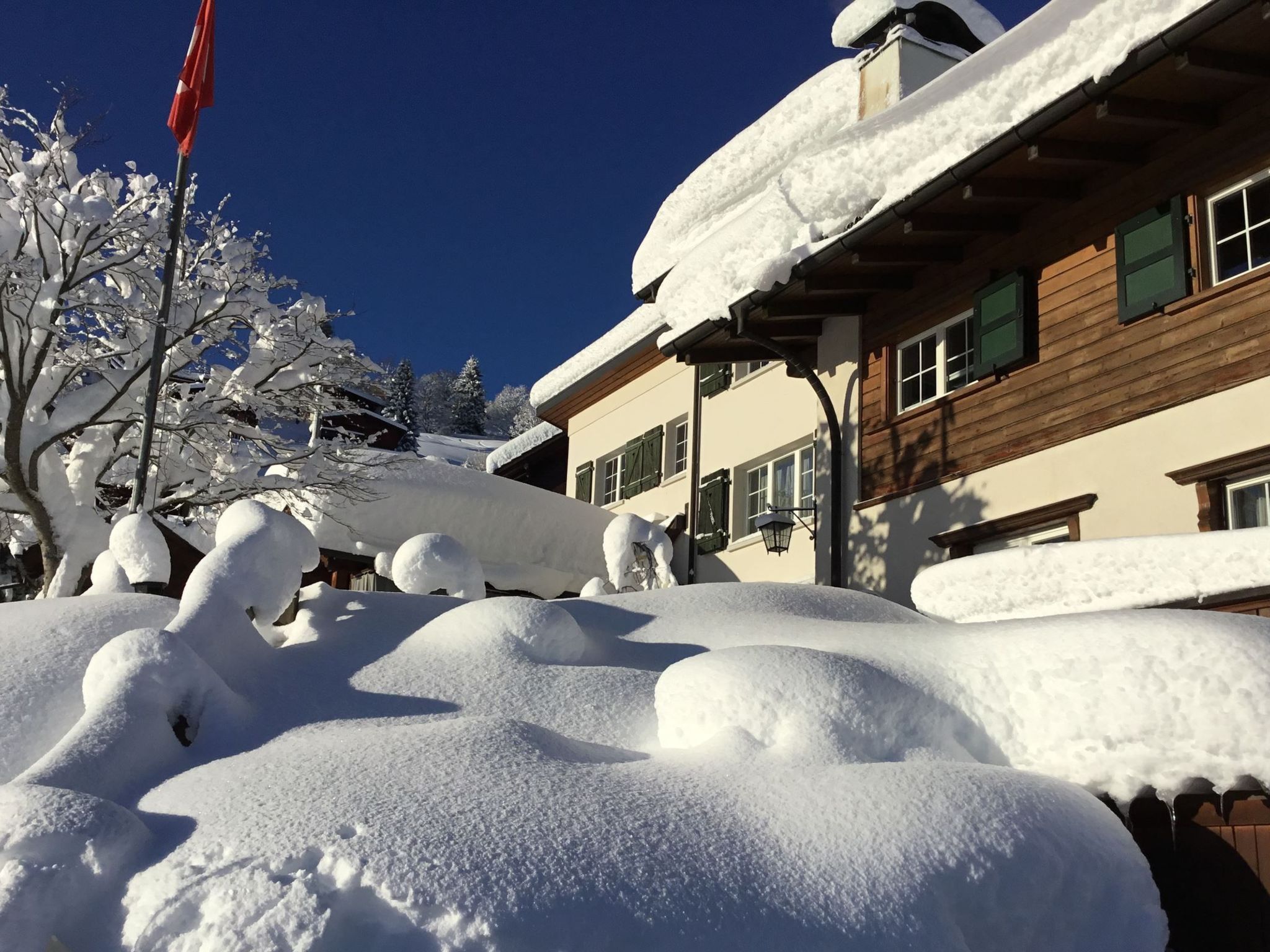 Ein mit Schnee bedecktes Gebäude mit einer Holzfassade und mehreren Fenstern.