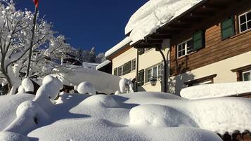 Ein mit Schnee bedecktes Gebäude mit einer Holzfassade und mehreren Fenstern.