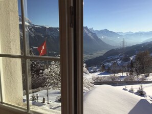 Blick aus dem Fenster auf eine verschneite Berglandschaft mit einer Flagge.