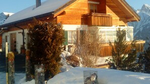 Eine Holzhütte mit Balkon, umgeben von Schnee und Bergen.