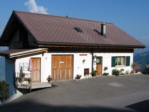 A two-story building with a sloped roof, wooden doors, and a small porch area.