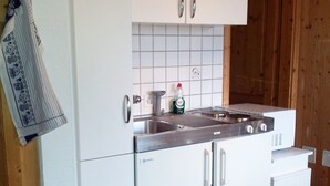 Eine Küche mit weißen Schränken, einer Edelstahl-Spüle und einem eingebauten Herd.