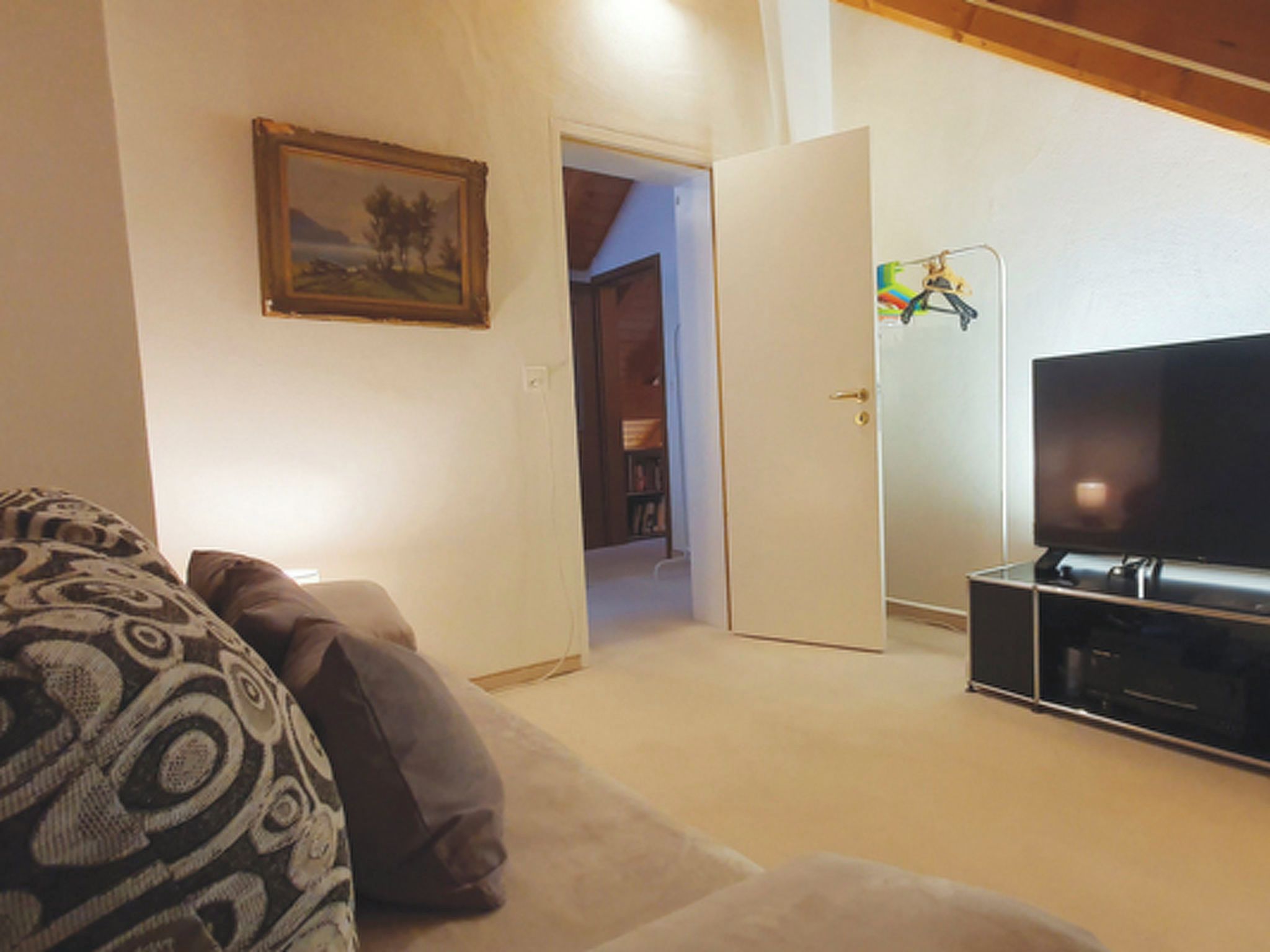 A living room with a sofa, a television, and a door leading to another room.