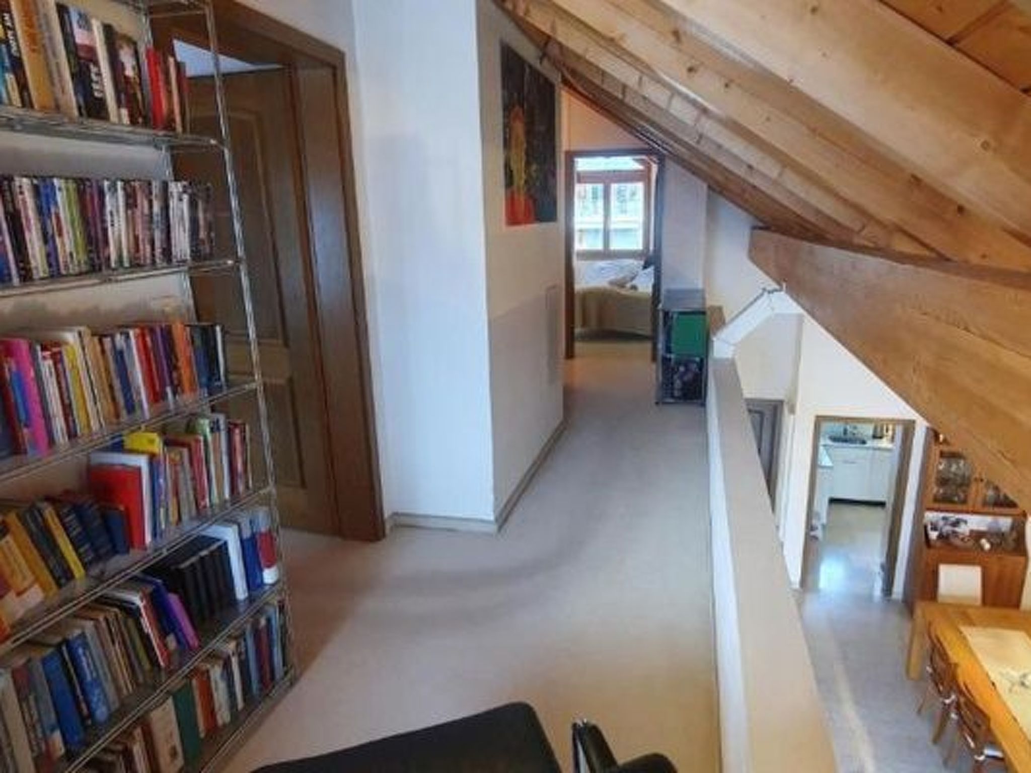Un pasillo estrecho con estanterías a un lado y una escalera al otro.