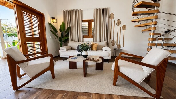 Een moderne woonkamer met een bank, twee fauteuils, een salontafel en een spiltrap.