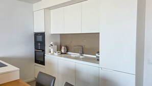 Une cuisine compacte équipée d’un four encastré, d’une machine à café et d’un évier.