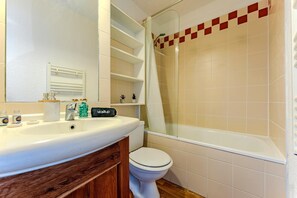 A bathroom with a white sink, a toilet, a shower with a glass door, and a mirror above the sink. - Residence Cuzco (Les Belleville)