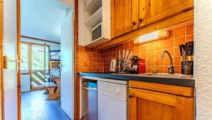 Een keuken met houten kastjes, een vaatwasser en een betegelde spatwand.