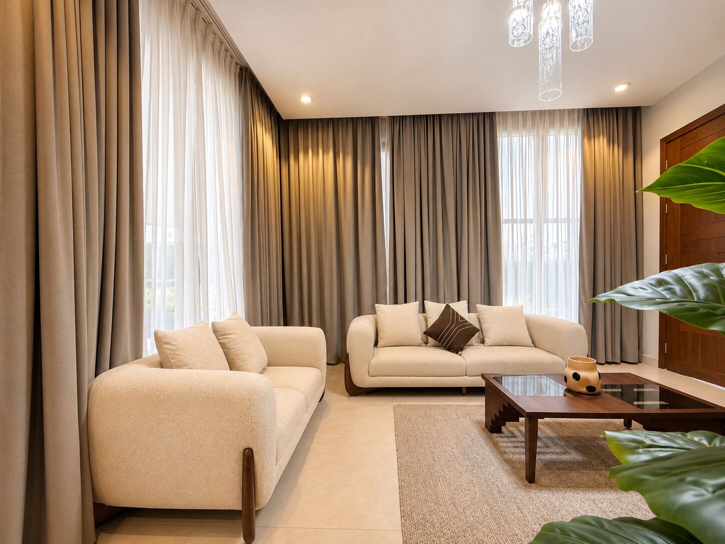 A modern living room with two sofas, a coffee table, and large windows with curtains.