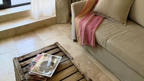 Een kamer met een bank, een lamp, een raam met gordijnen en een houten tafel met tijdschriften.
