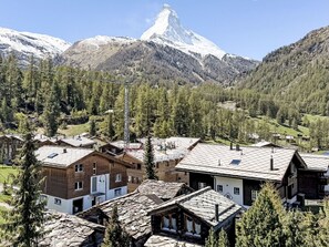 Un village de montagne aux maisons traditionnelles en bois, doté d’un télésiège et surplombé d’un sommet enneigé.