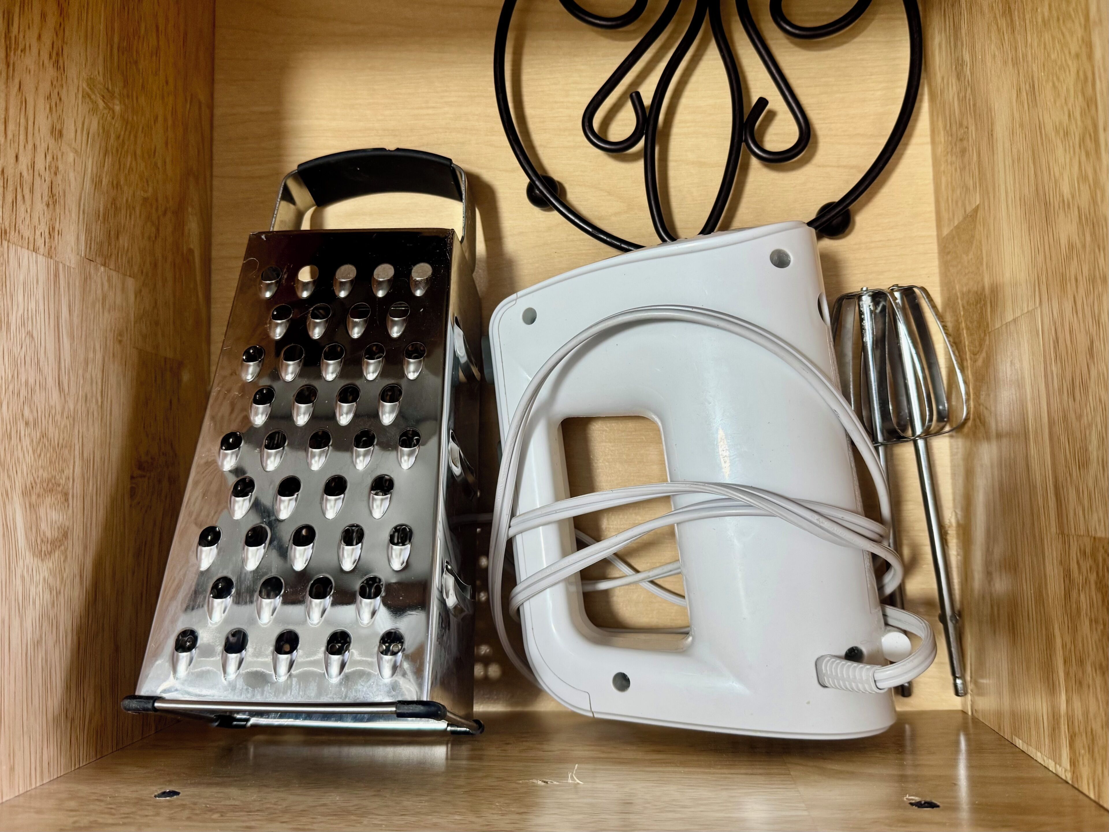 Une cuisine équipée d’une râpe, d’un appareil électroménager blanc et d’un ustensile de cuisine en métal.