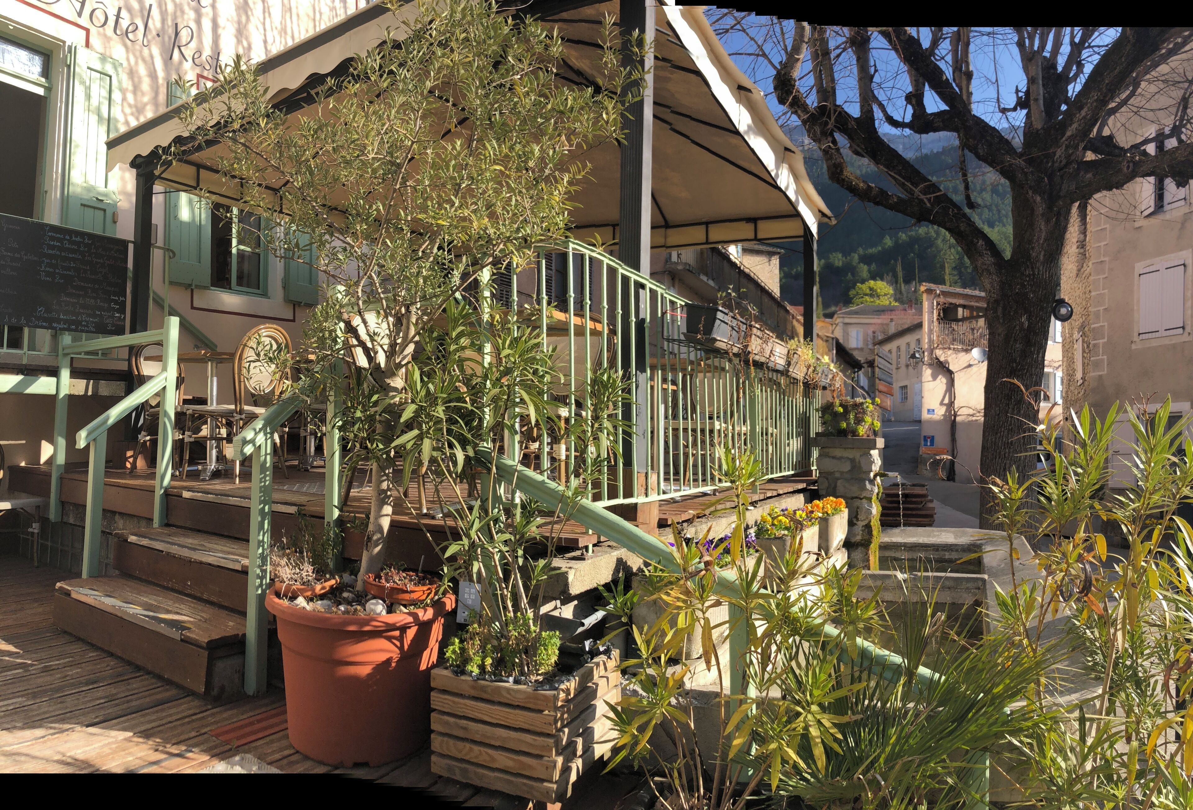 A hotel with outdoor seating, a staircase, and potted plants.