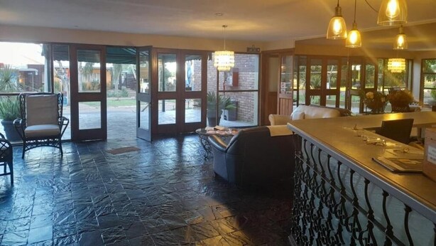 A spacious room with a stone floor, a bar area, and large glass doors leading to an outdoor area.