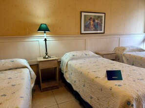 A hotel room with two single beds, a nightstand with a lamp, a framed picture on the wall, and a blue booklet on one of the beds. - Nobile Hotel Solar del Acuario  (Termas del Dayman)