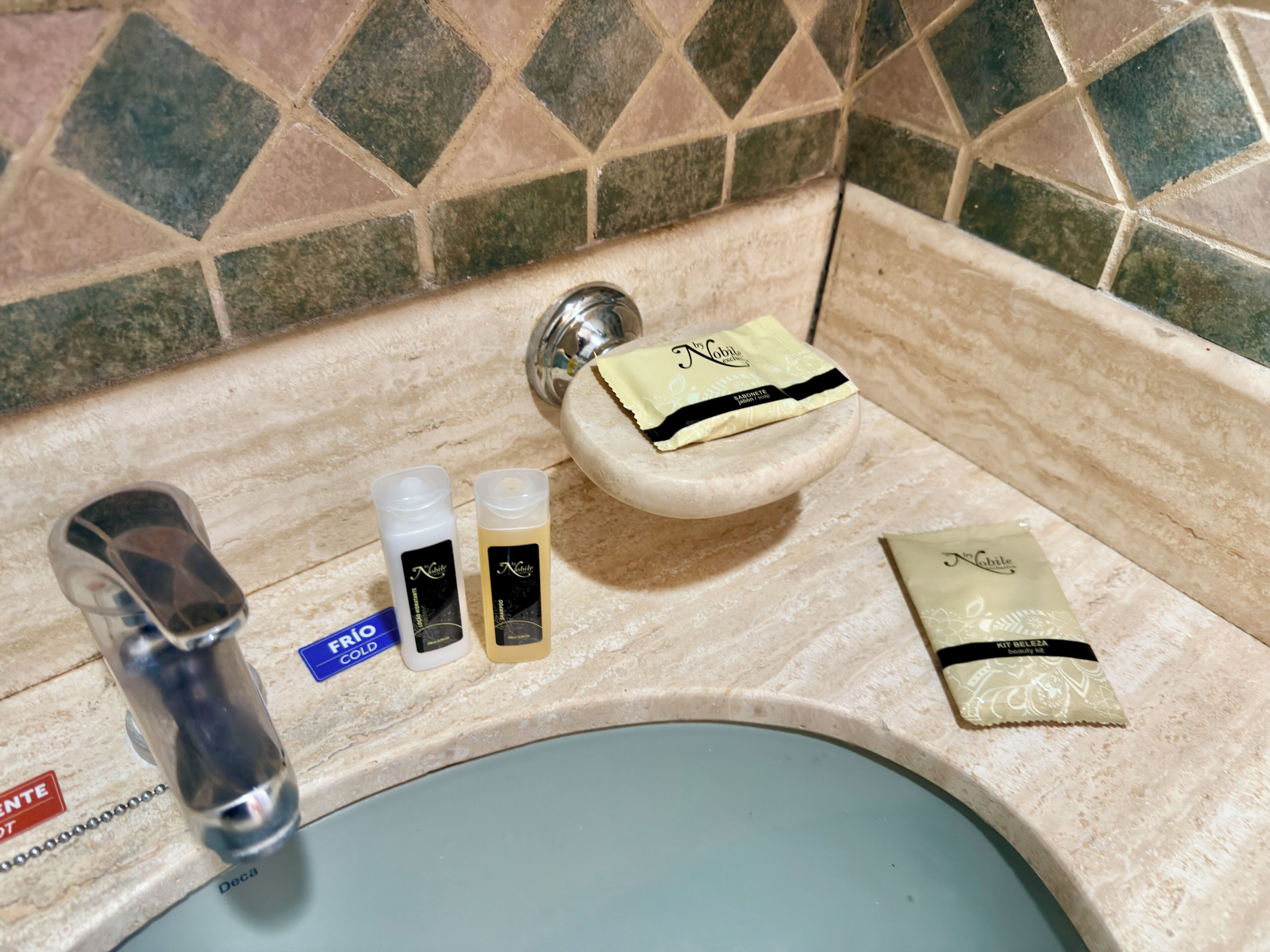 A bathroom sink with toiletries including a soap bar, two bottles, and a small packet.