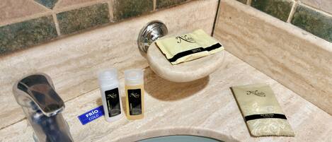 A bathroom sink with toiletries including a soap bar, two bottles, and a small packet.