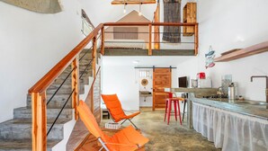Un espacio tipo loft con escalera de madera, zona de cocina y comedor.