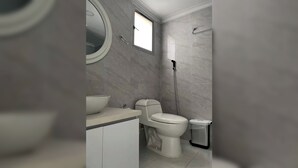 A bathroom with a toilet, bidet, sink, mirror, and a window. - Prime Bocagrande 3BR with AC, Parking, Near Beach & Bay Tours (Cartagena de Indias)