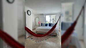 A bedroom with a bed, a hammock, a clock, and a window. - Prime Bocagrande 3BR with AC, Parking, Near Beach & Bay Tours (Cartagena de Indias)