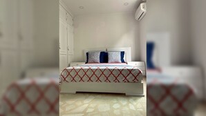 A bedroom with a bed, a wardrobe, and an air conditioning unit. - Prime Bocagrande 3BR with AC, Parking, Near Beach & Bay Tours (Cartagena de Indias)