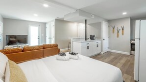 Een moderne hotelkamer met een groot bed, een bank, een kitchenette en een televisie.