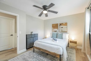 A bedroom with a bed, a ceiling fan, a dresser, and two bedside tables with lamps.