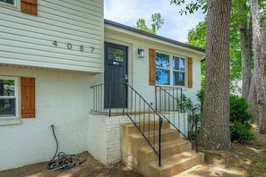 A single-story house with a front porch, a black front door, and a staircase leading to the entrance.