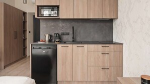 Een moderne keuken met houten kastjes, een ingebouwde magnetron, een koffiezetapparaat en een vaatwasser.