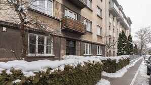 En boligbygning med murstensfacade, flere vinduer og en lille balkon.