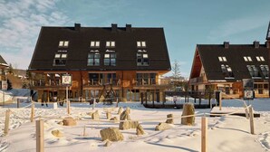 Ett hotell med ett mörkt tak, många fönster och en träfasad.