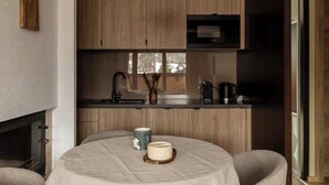 A modern kitchen with wooden cabinets, a round table with a tablecloth, and a coffee maker. - Butorowy Residence | Sauna & Gym | Mountain View (Kościelisko)