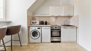Une petite cuisine équipée comprenant un lave-linge, un four à micro-ondes, un four et un évier.