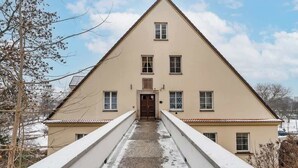 Un bâtiment symétrique doté d’une entrée centrale, de deux ailes et d’un toit en pente.