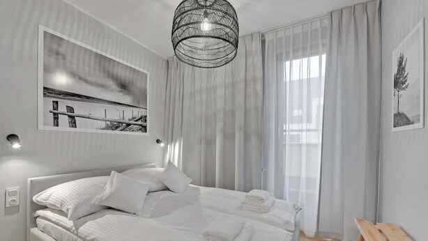 Ein modernes Schlafzimmer mit einem großen Bett, einer hölzernen Bank und einer Pendelleuchte.
