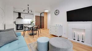 Ein modernes Wohnzimmer mit einer Couch, einem Hocker und einem an der Wand befestigten Flachbildfernseher.