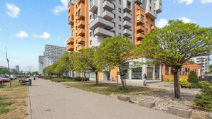 Ein modernes Mehrfamilienhaus mit Pflasterweg und Bäumen.