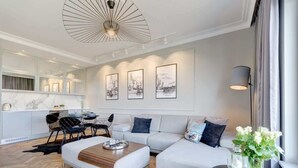 A modern living room with a sofa, coffee table, and artwork on the wall. - Brabank Superior | Riverside & Balcony | Parking (Gdańsk)