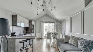 Uma cozinha moderna com uma ilha central, banquetas de bar e um espaço de refeições com mesa e cadeiras.