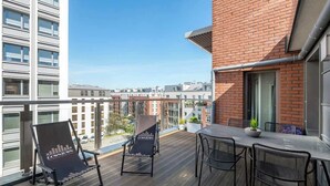 Ein Balkon mit Tisch und Stühlen, einer Topfpflanze und Blick auf eine Stadtansicht.