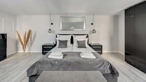 Ein modernes Schlafzimmer mit einem großen Bett, Nachttischen, einer Kommode und einem Kleiderschrank.