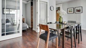 Un espace repas moderne avec une table à manger en bois, des chaises noires et un vase vert orné de fleurs.