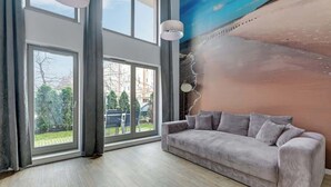 Ein modernes Wohnzimmer mit großem Fenster, einer Couch und einer Wandmalerei.