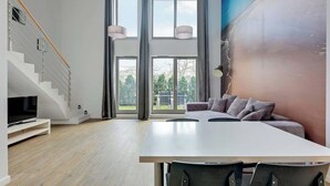 Ein modernes Wohnzimmer mit Treppe, Essbereich und einem großen Fenster mit Aussicht.
