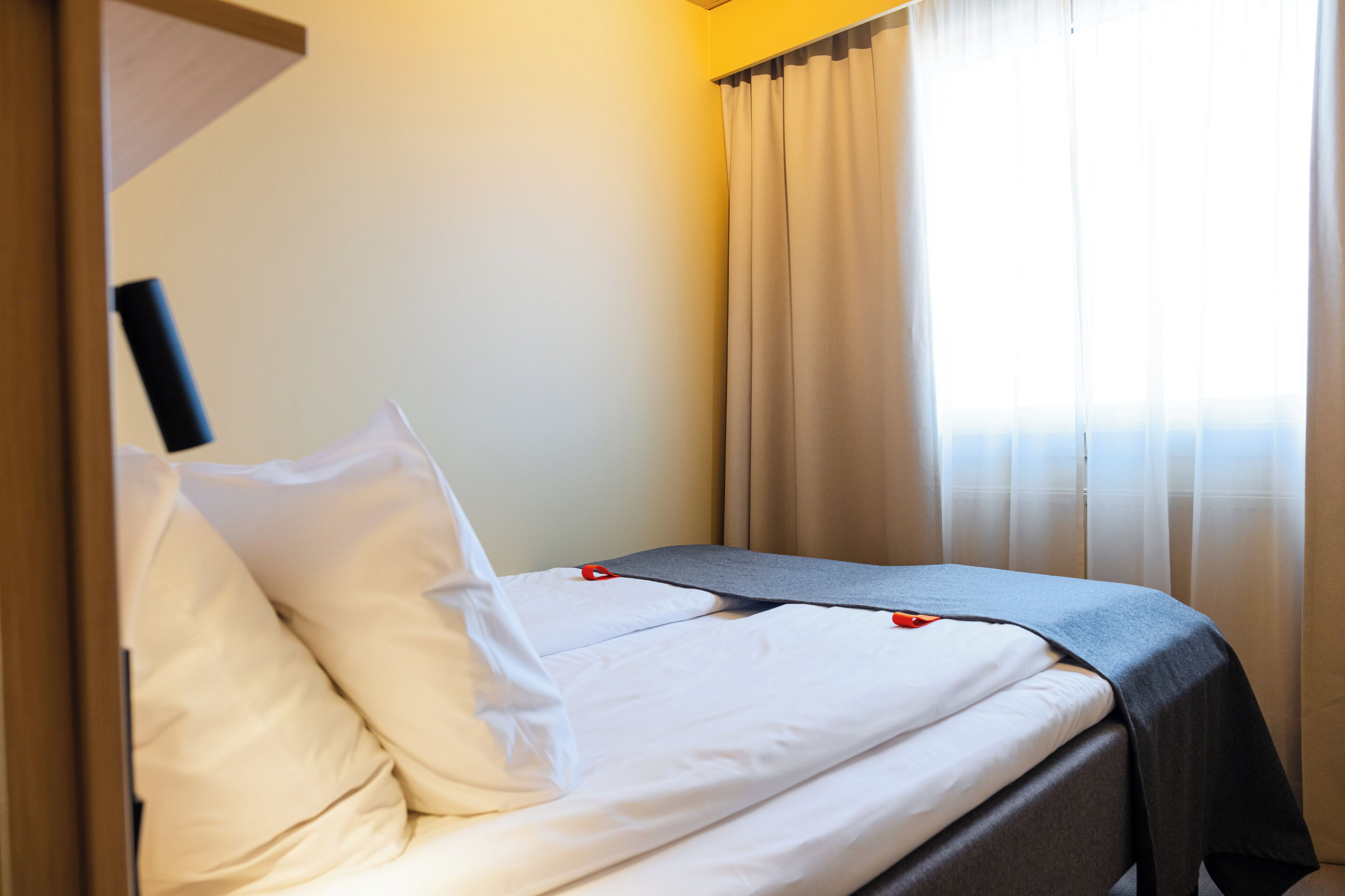 A hotel room with a bed, curtains, and a window.
