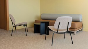 A room with a sofa, two chairs, and a small table.