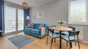 A modern living room with a blue sofa, a round wooden table, and black chairs. - Navio with Balcony | Seaside (Gdańsk)