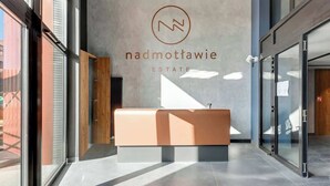 A reception area with a modern design, a logo, and the name 'nadmottawie estate' on the wall. - Nadmotławie C14 | Riverside | Sauna & Gym (Gdańsk)