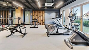A gym with cardio machines, weightlifting equipment, and a large window. - Nadmotławie C42 | Riverside | Sauna & Gym (Gdańsk)